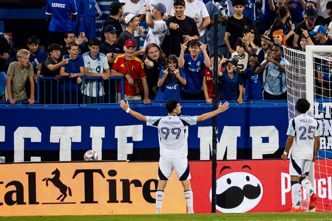 A soccer player celebrates his goal in front of fans of the opposing team.