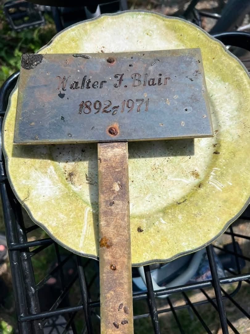 A photo of a grave marker laying on a greened plate. It reads 'Walter F. Blair 1892 - 1971.'