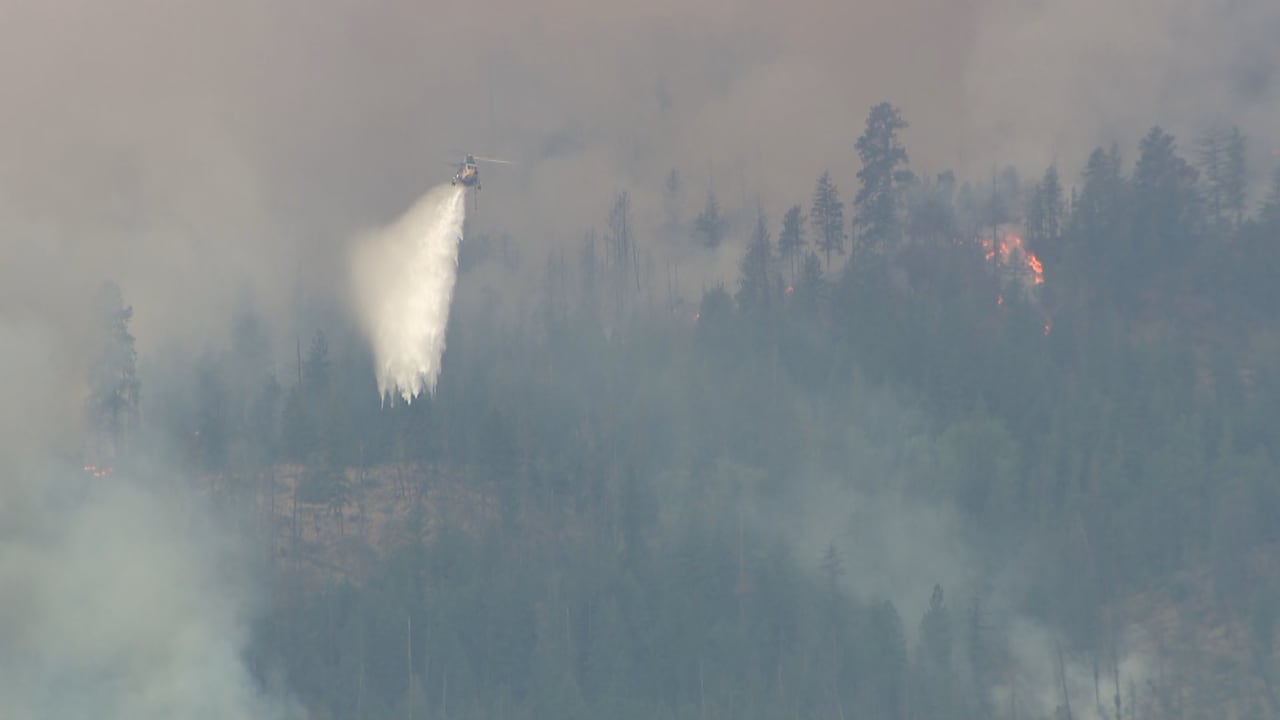 A firefighting helicopter is pictured dumping water on a blaze.