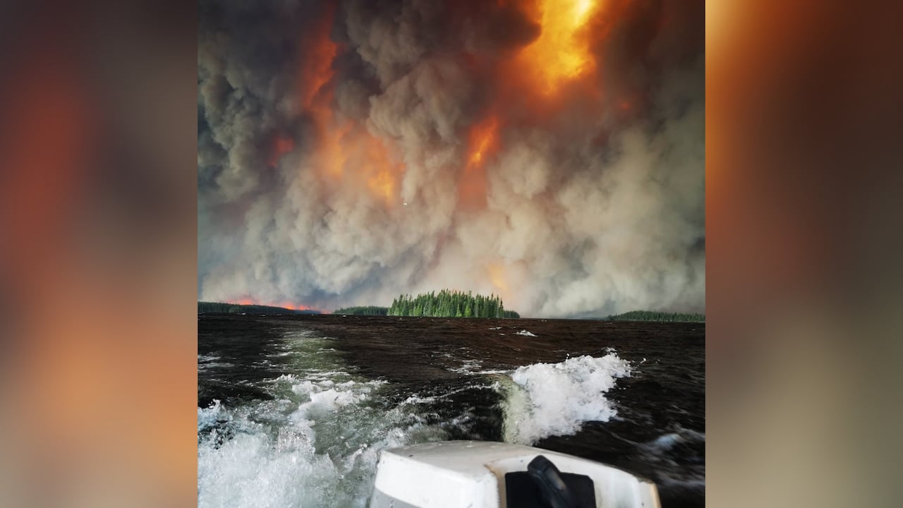 A wildfire is seen above a land mass in the water.