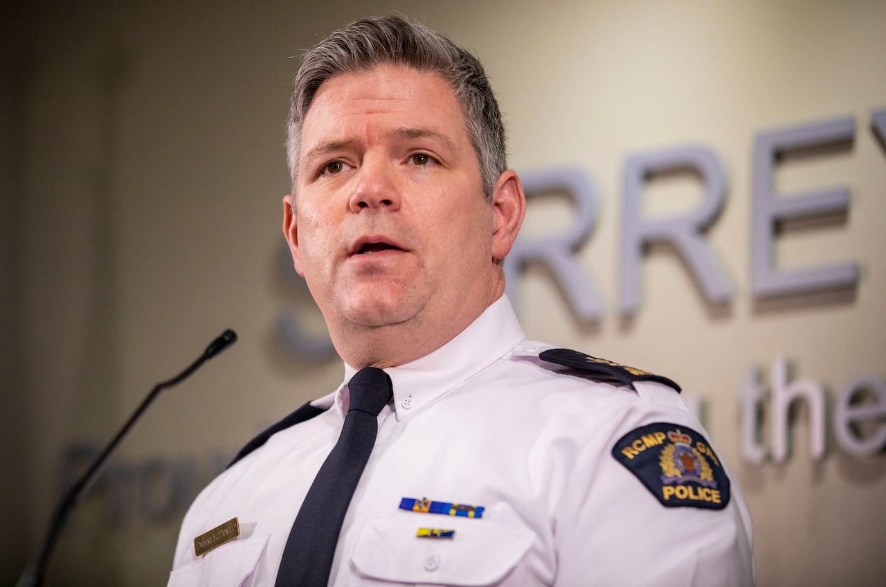 A police officer speaks in front of a blue background.