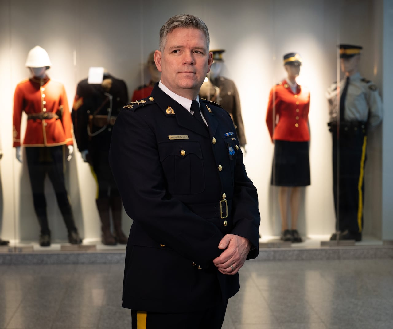 A police officer in a blue uniform is seen in front of mannequins.