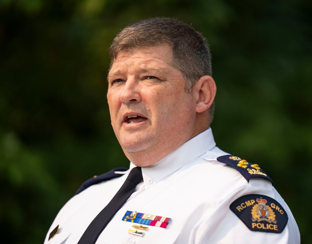 A police officer wearing a white shirt with an RCMP badge speaks.