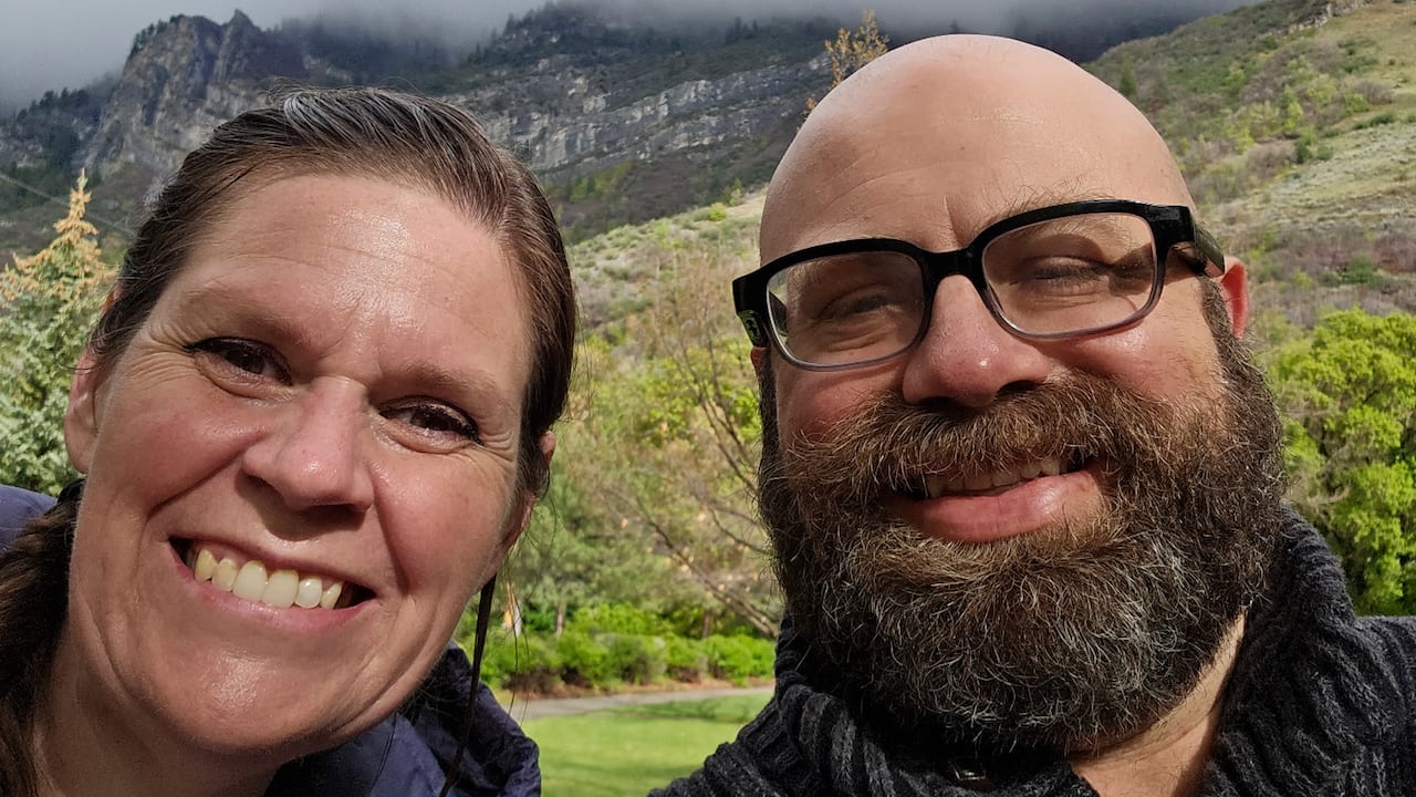 A man and woman smiling with mountains behind them