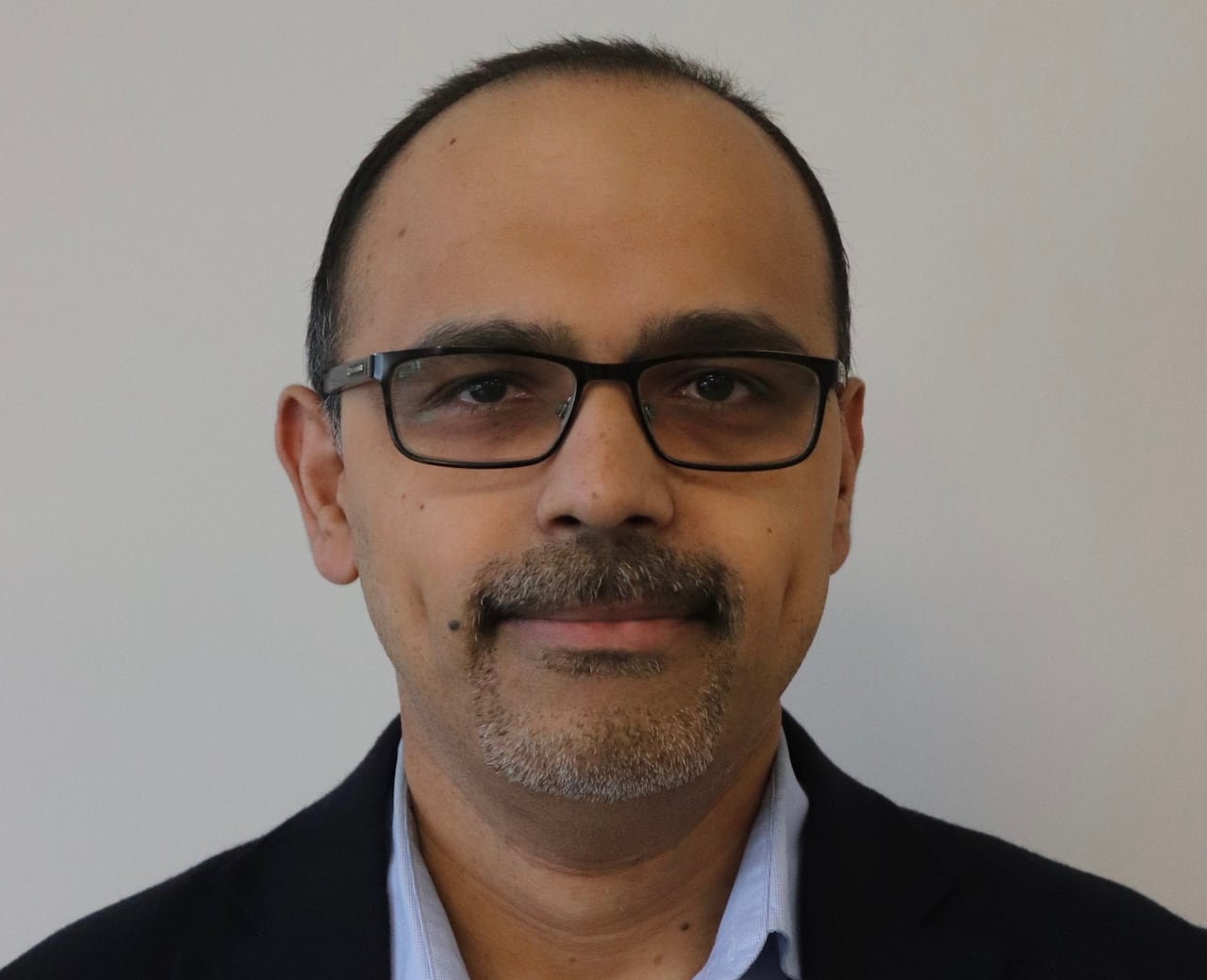 A spectacled man smiling