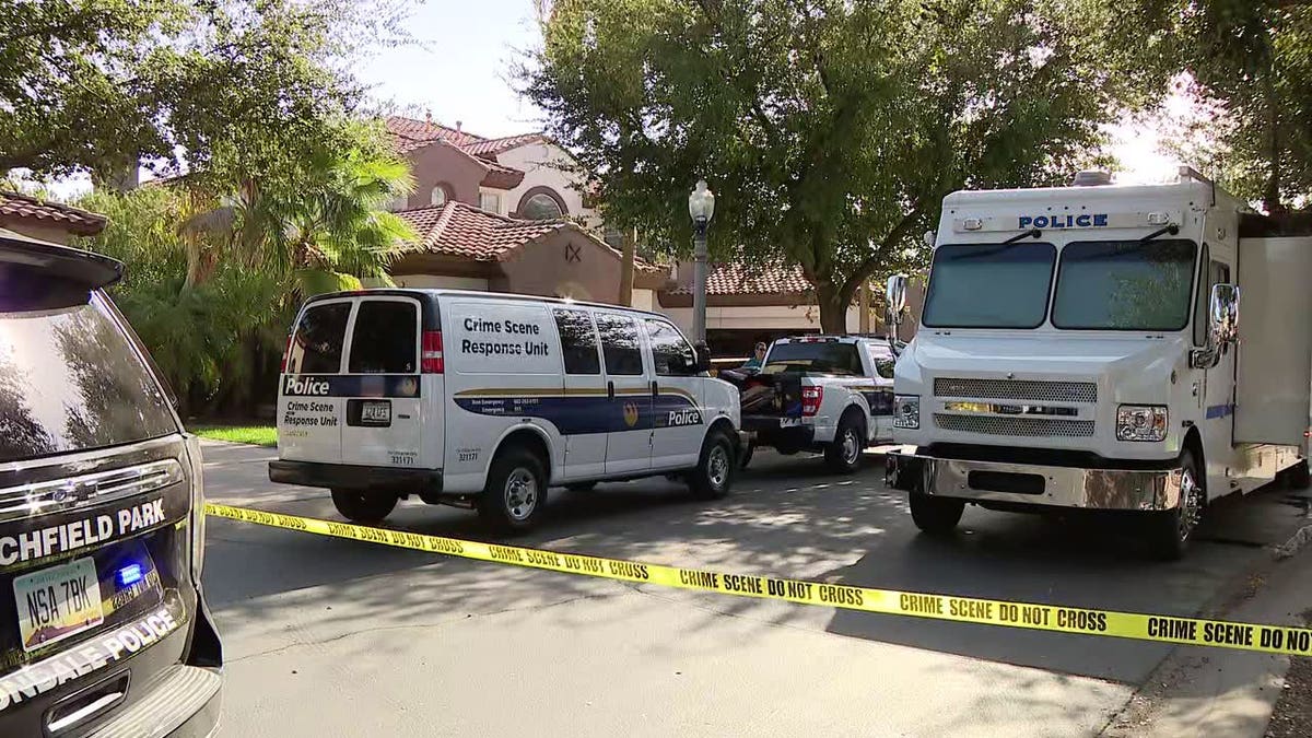 Police vehicles, including a Crime Scene Response Unit van, parked behind yellow crime scene tape outside a home.