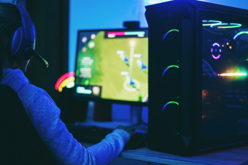 Gamer in dark playing a sports game on PC.