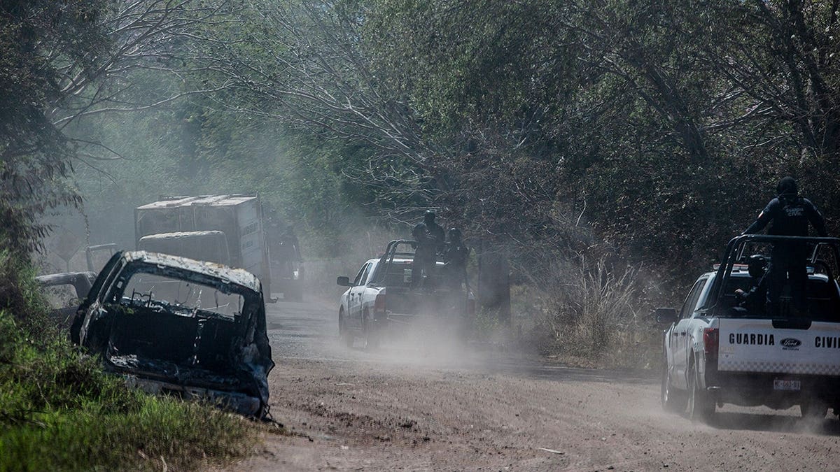 Civil Guard of Michoacan members patrol a highway near a burned truck in Aguililla, Mexico.