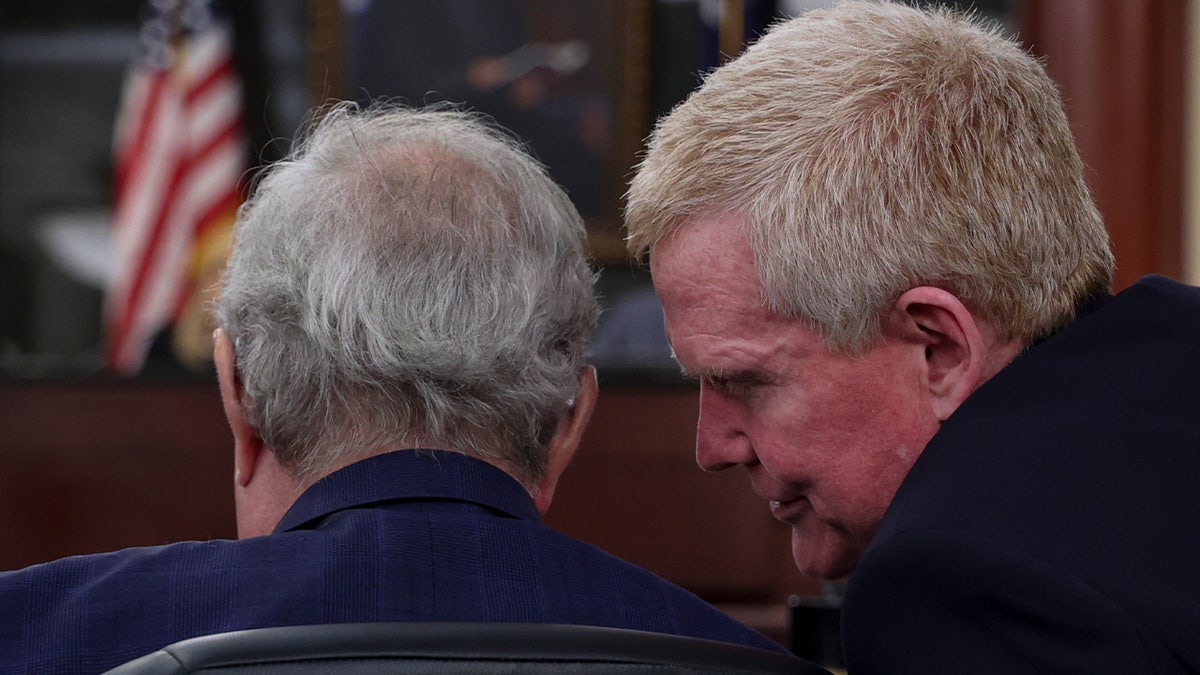 Alex Murdaugh sits in a courtroom as defense attorney Richard A. Harpootlian leans in to speak with him.