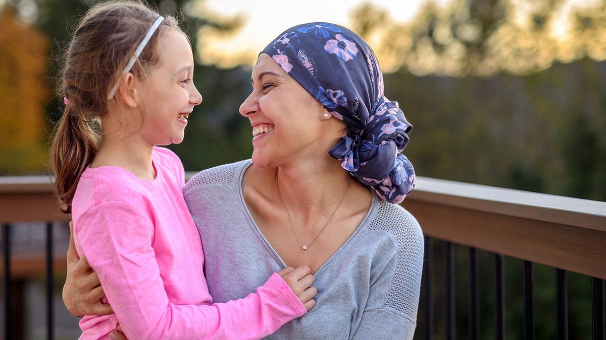 A cancer survivor smiles at a child she's holding.