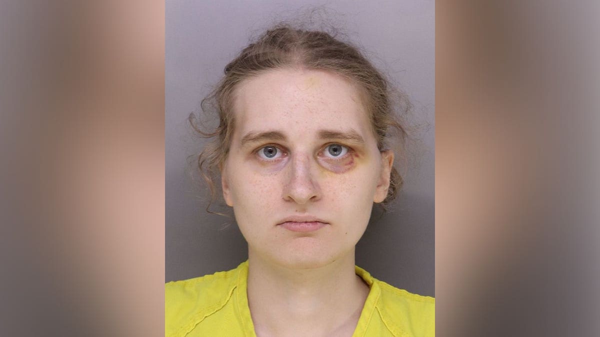 Alt text: Booking photo of Nessa Keaney wearing a yellow jail uniform against a gray background.