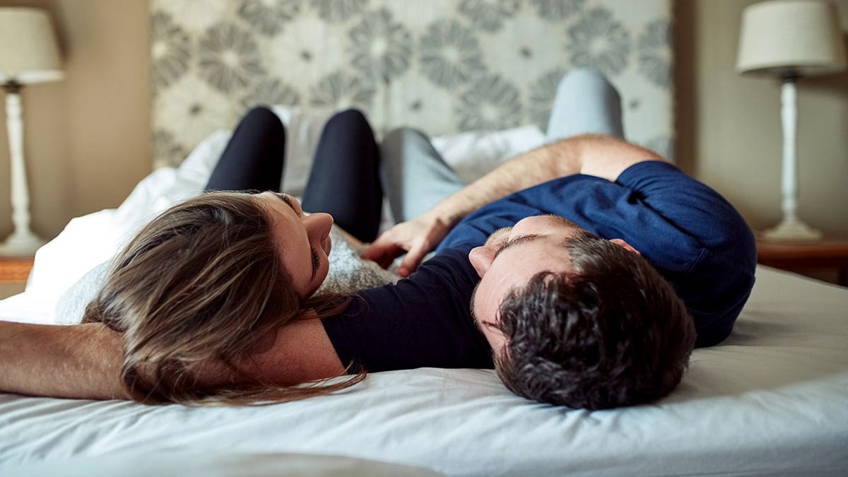 A young couple shares a romantic moment in bed at home.