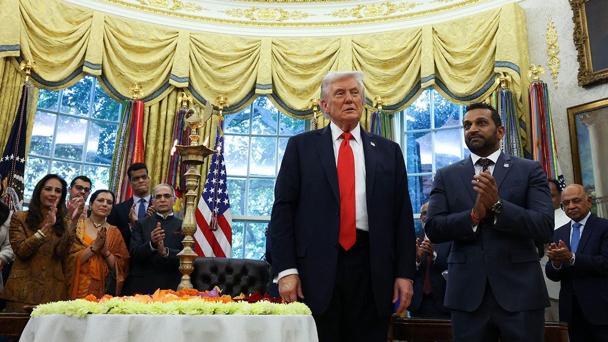 Donald Trump and Kash Patel light a diya candle during a Diwali event in the Oval Office.