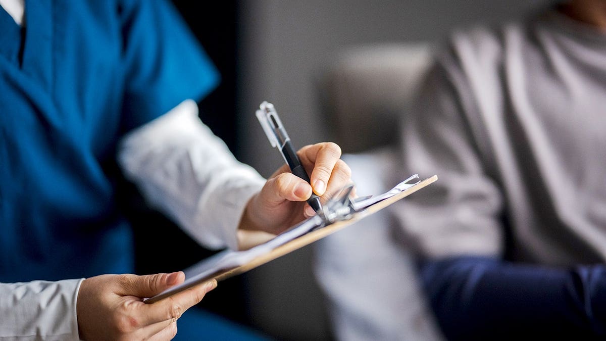 Female doctor on a home visit consulting with a patient and pharmacist.