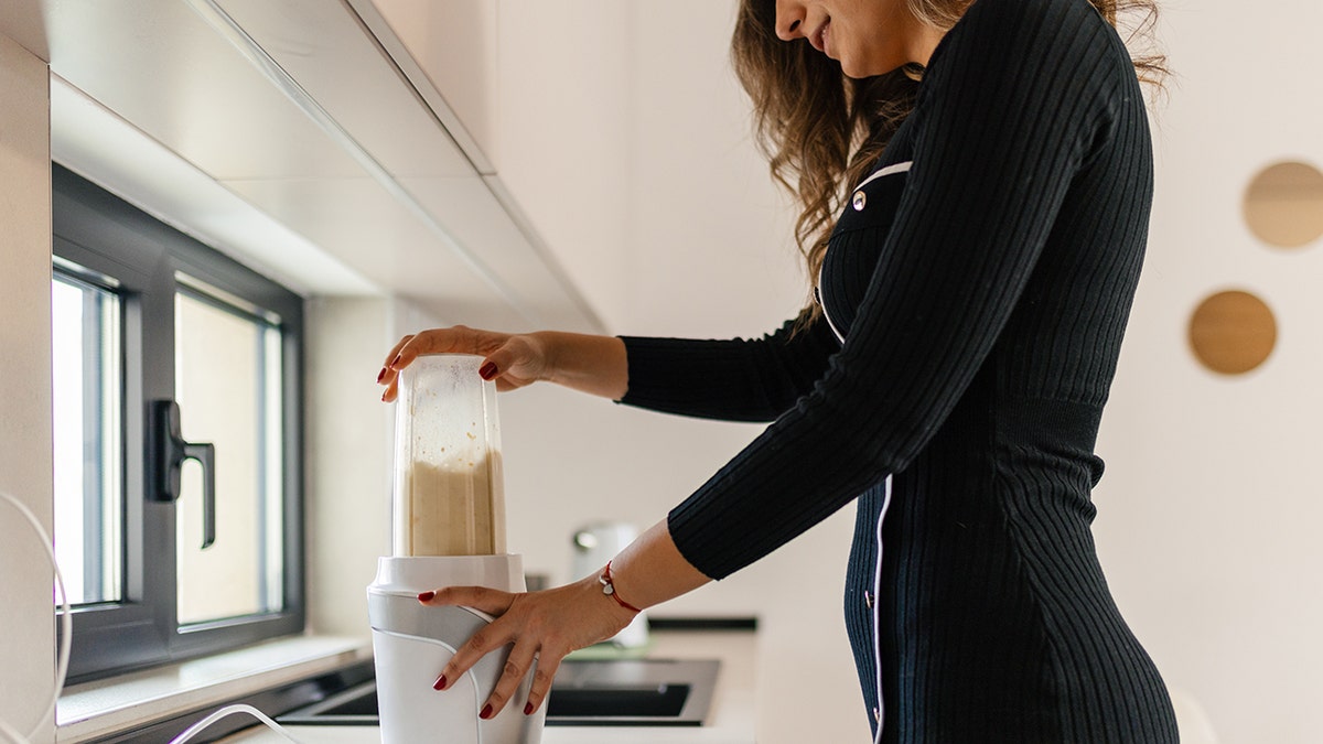 woman blends a smoothie in a blender