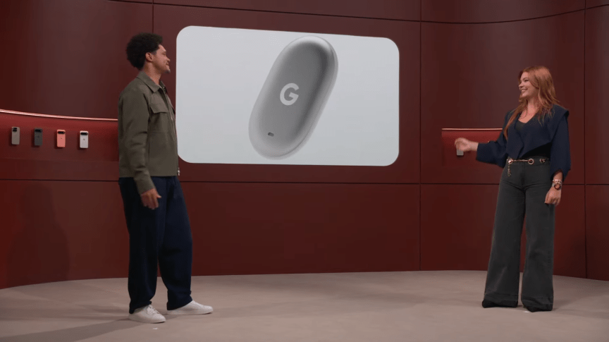 A man and woman stand in front of a screen that displays a Google Tag.