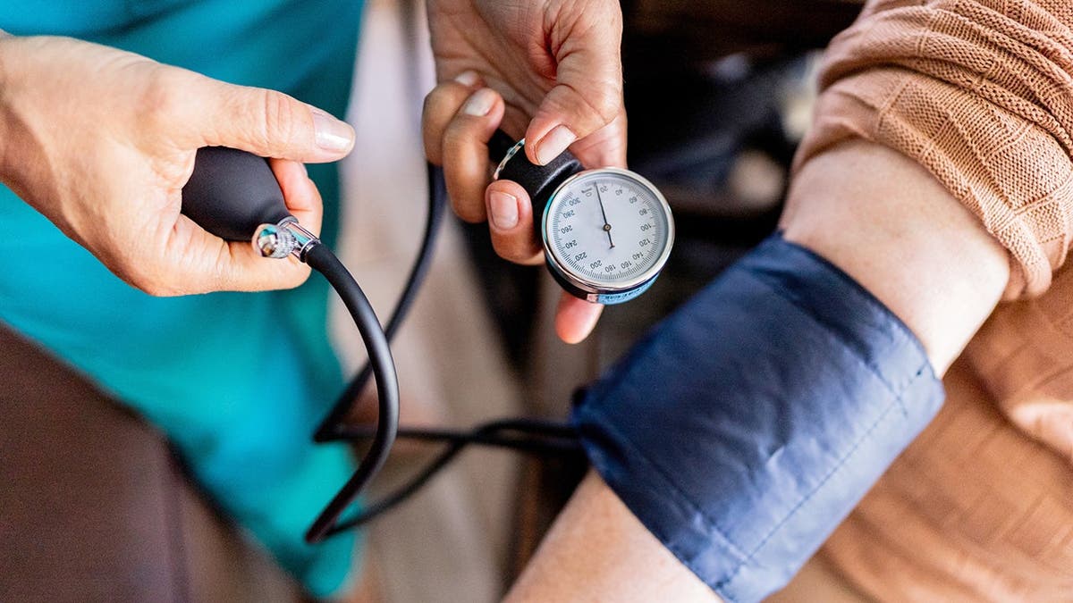 A woman reads the blood pressure of a patient.