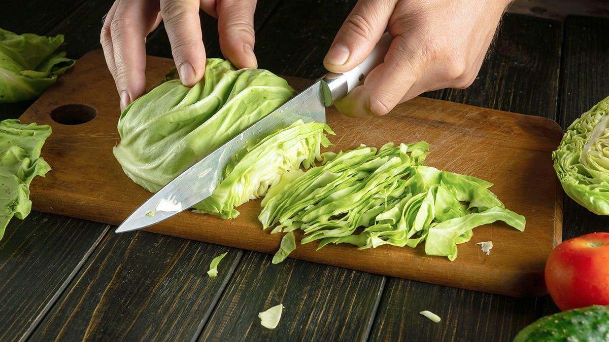 A person chops lettuce on a table.