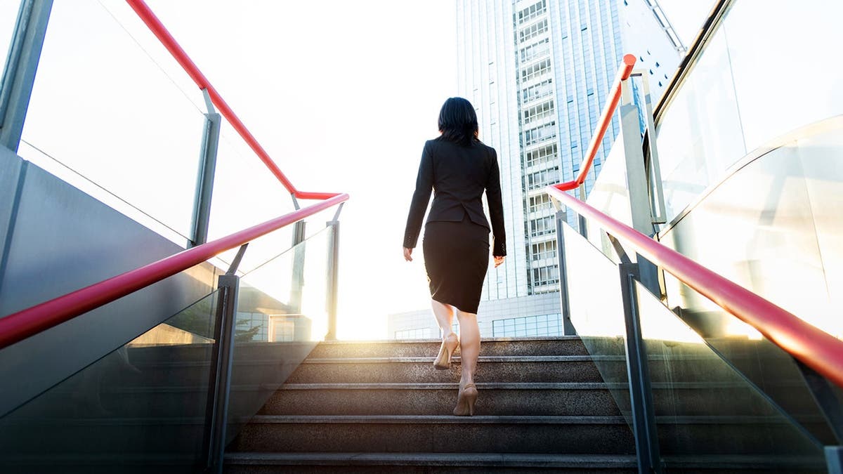A business woman walks up a flight of steps in a public space.