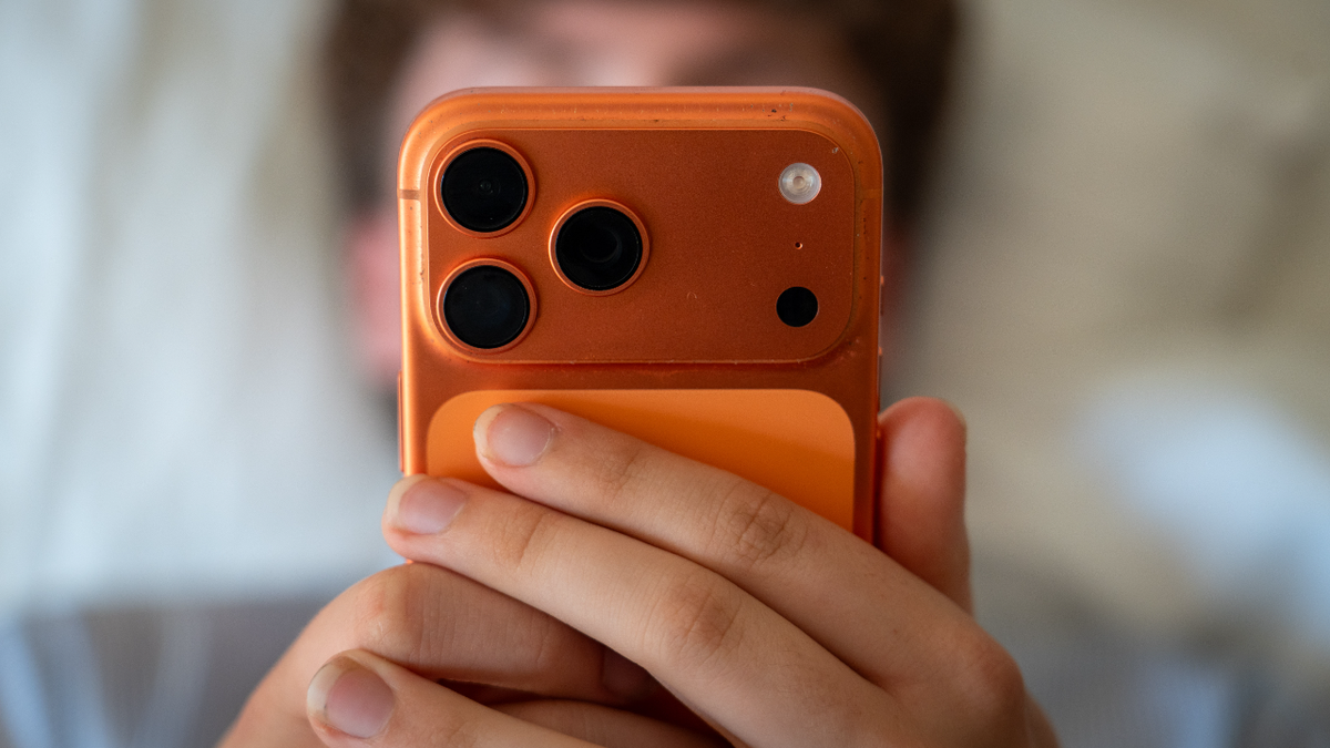 Teenage boy uses iPhone while lying in bed.