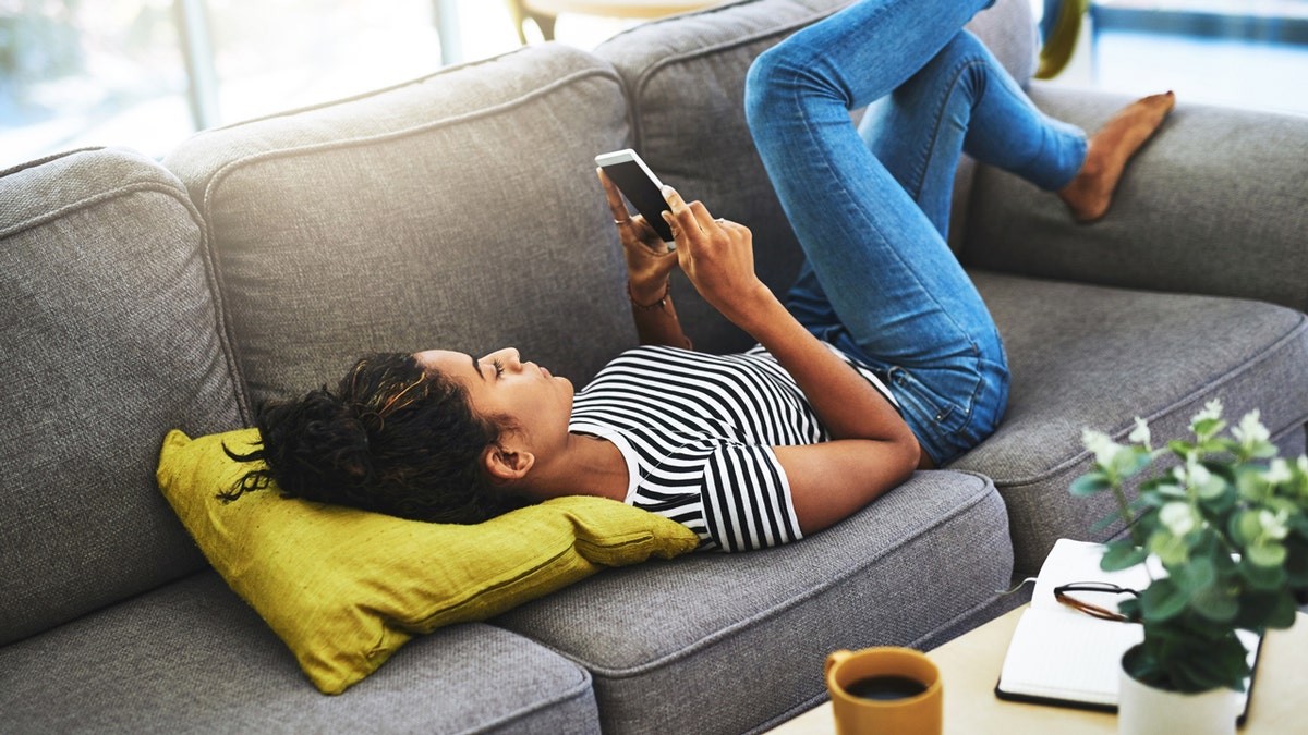 Woman scrolling on her phone on couch