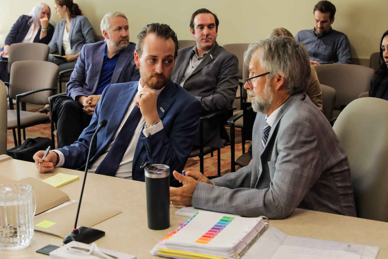 Two people sit at a table in a meeting room.