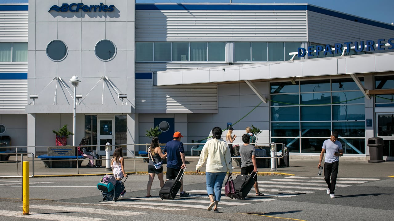 People are pictured wheeling suitcases on their way to a B.C. Ferries terminal.