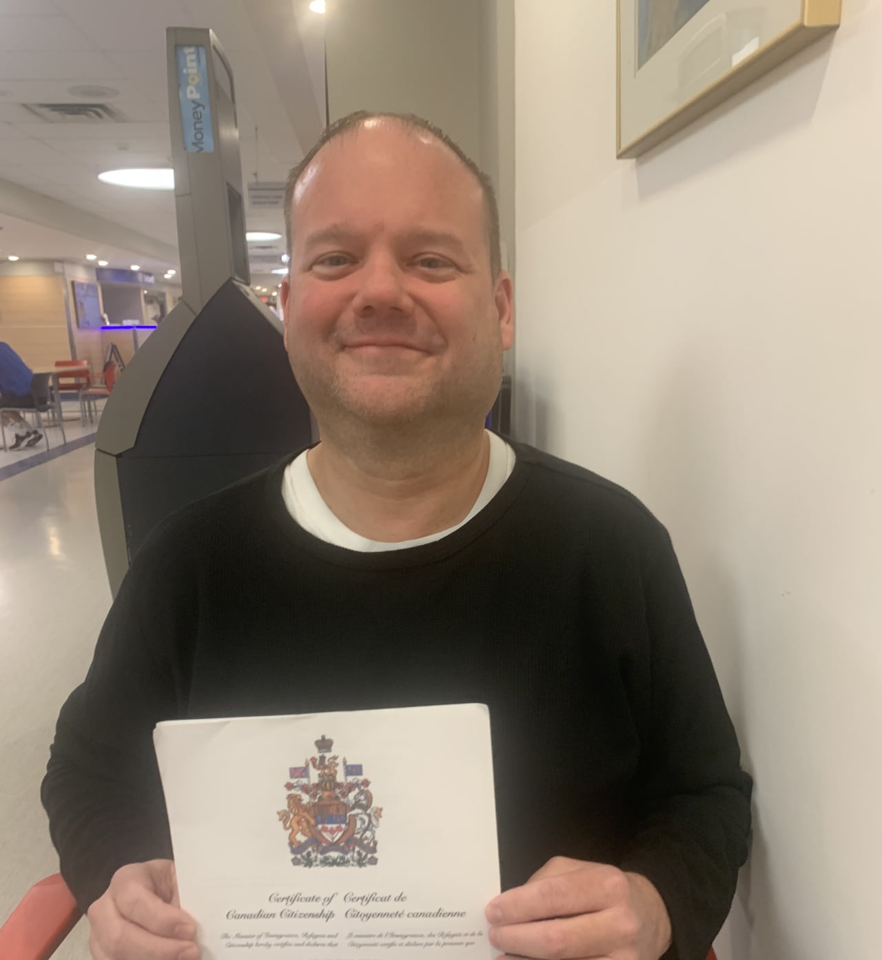 Man holding Canadian citizenship certificate.