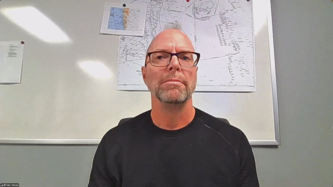 Man wearing glasses in dark shirt.
