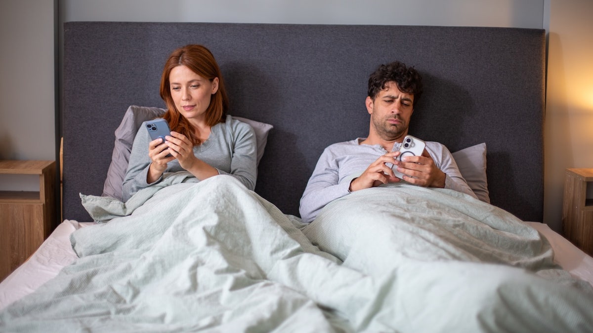 Couple in bed on phones