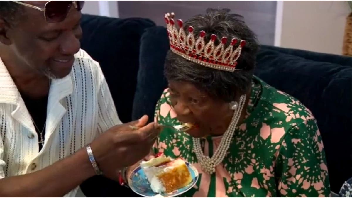 A relative feeds Mabel Dunbar a bite of cake.