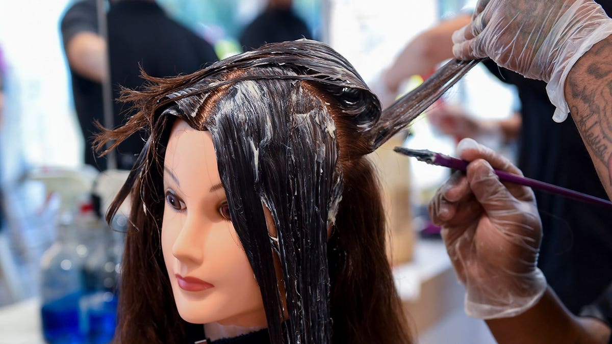 Tyneisha Bell applies color to a mannequin head at a beauty academy.